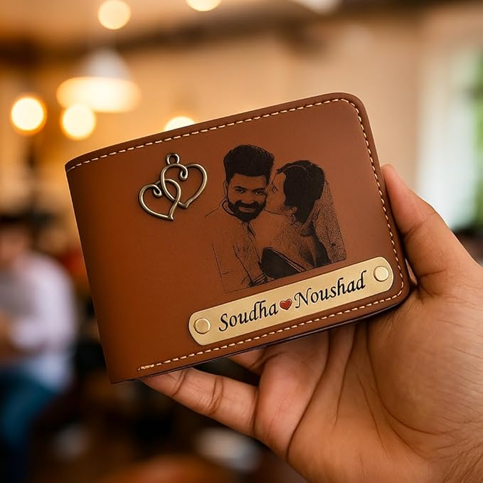 Brown leather wallet with engraved couple and personalized name, held in a hand.